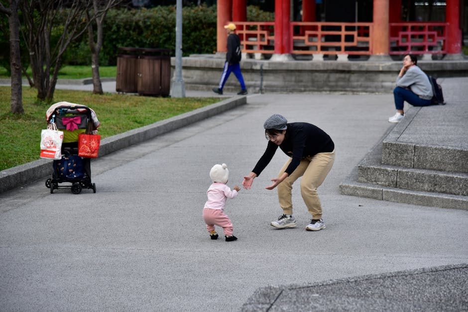 母親が市内の公園で幼児に喜びながら手を伸ばしている。